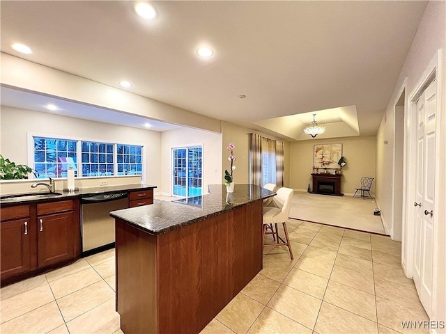 kitchen featuring dishwasher, light tile patterned floors, a kitchen bar, a kitchen island, and sink