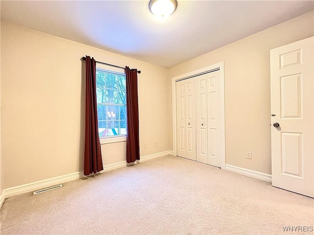 unfurnished bedroom with a closet and light carpet