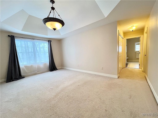 unfurnished room featuring light carpet and a tray ceiling