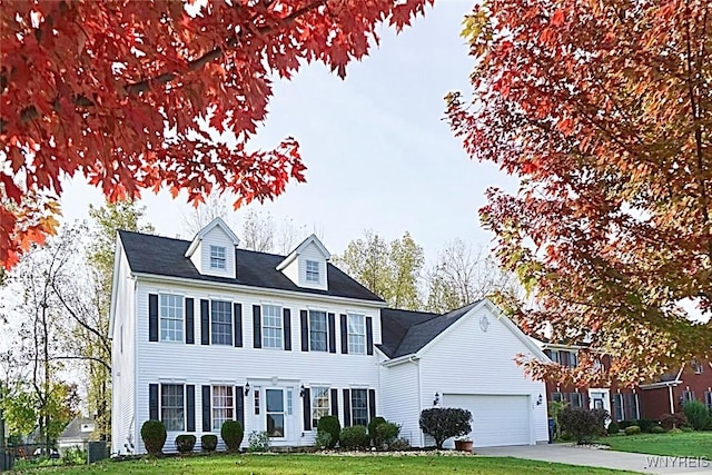 colonial-style house featuring a garage and a front yard