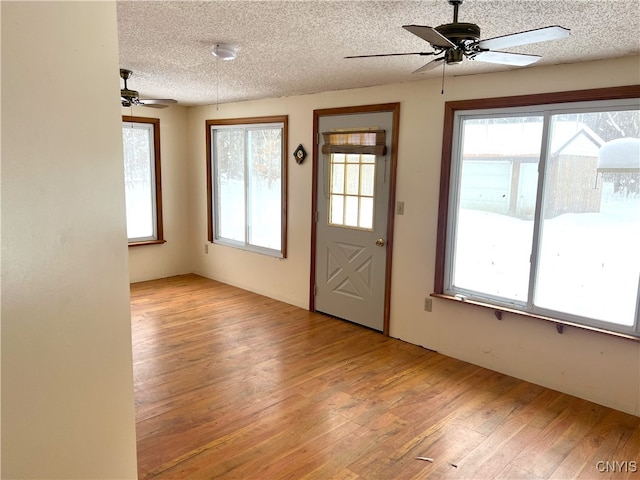 foyer with ceiling fan, a textured ceiling, and light wood-type flooring