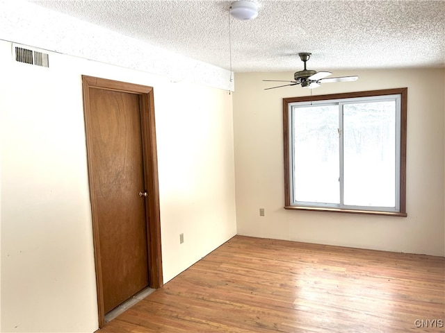 spare room with ceiling fan, a textured ceiling, and light wood-type flooring