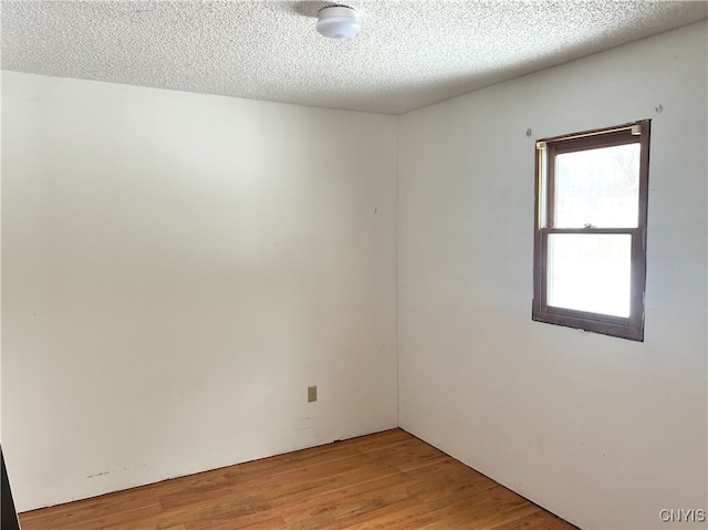 unfurnished room featuring light hardwood / wood-style flooring and a textured ceiling