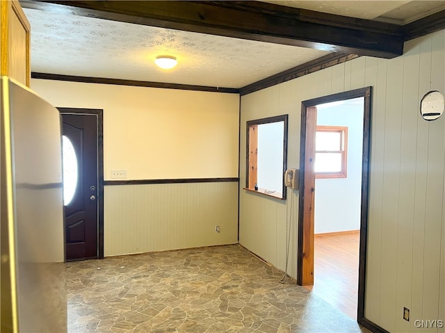 unfurnished room featuring crown molding, beamed ceiling, and a textured ceiling