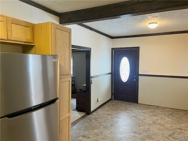 foyer entrance with ornamental molding, beam ceiling, and a textured ceiling