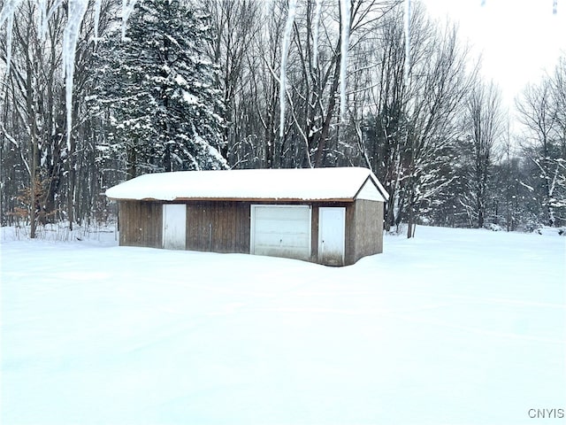 snow covered structure with a garage