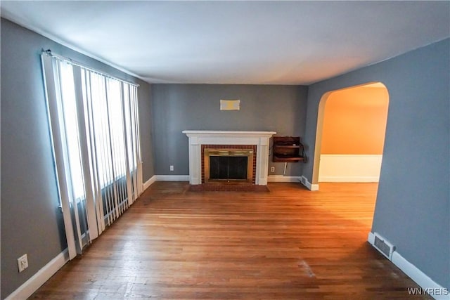 unfurnished living room featuring a brick fireplace and wood-type flooring