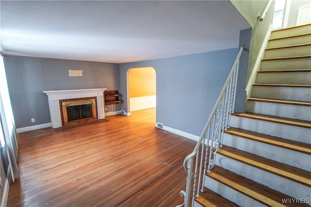 staircase with a fireplace and hardwood / wood-style flooring