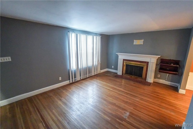 unfurnished living room with a brick fireplace and hardwood / wood-style flooring