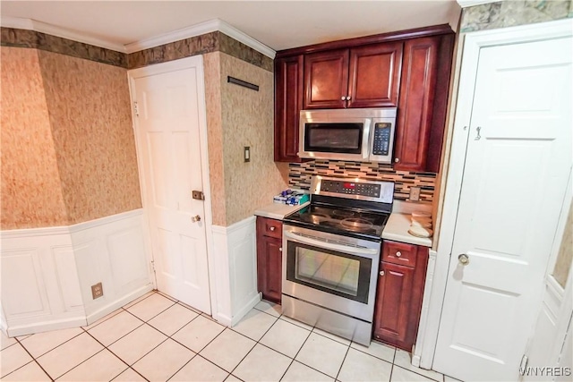 kitchen with stainless steel appliances, light tile patterned flooring, and ornamental molding