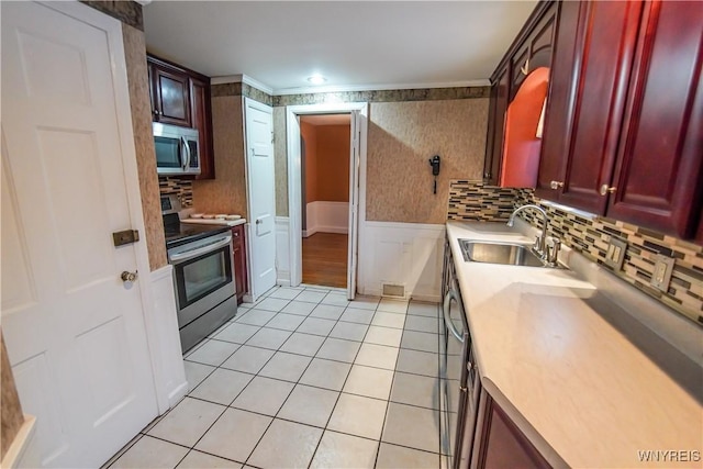 kitchen with appliances with stainless steel finishes, crown molding, sink, and light tile patterned floors