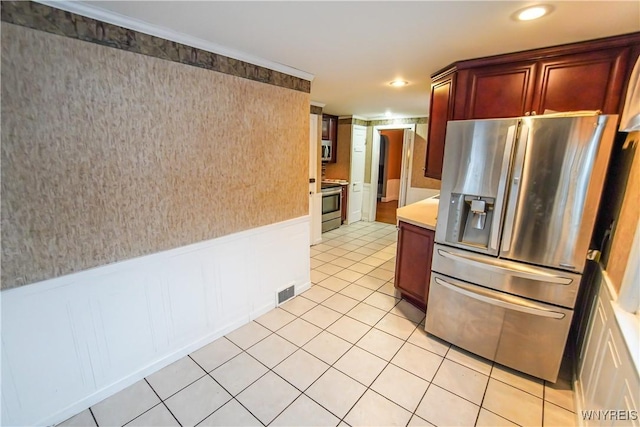 kitchen with appliances with stainless steel finishes, crown molding, and light tile patterned floors