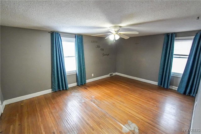 unfurnished room with plenty of natural light, a textured ceiling, ceiling fan, and hardwood / wood-style floors