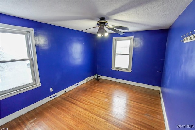 empty room with ceiling fan, a textured ceiling, and wood-type flooring