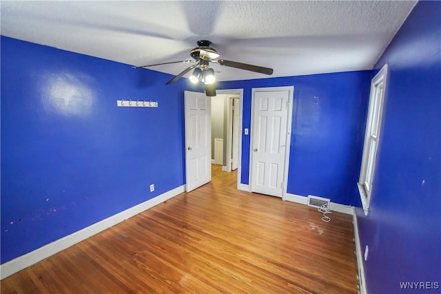 unfurnished bedroom with ceiling fan, a textured ceiling, and wood-type flooring