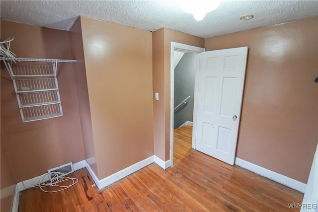 hallway with a textured ceiling and hardwood / wood-style flooring