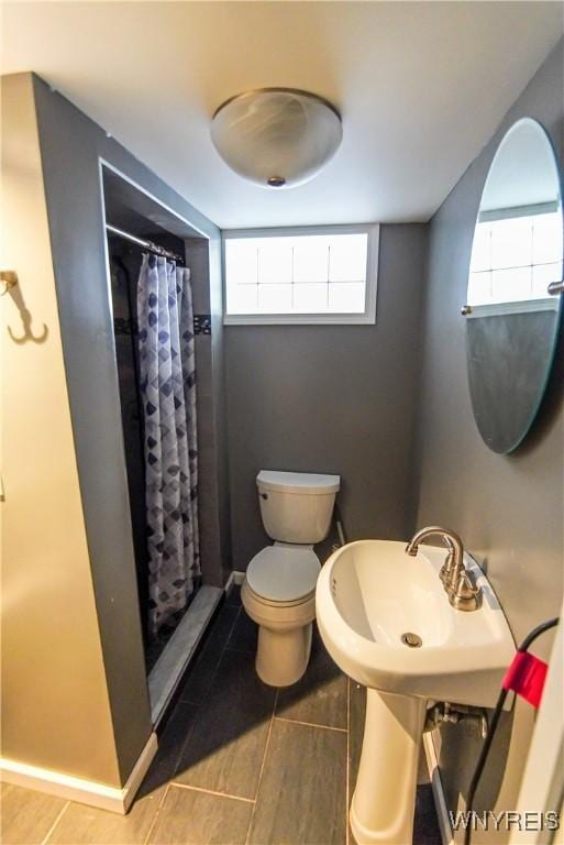 bathroom featuring toilet, a shower with shower curtain, and sink