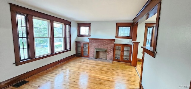 living room with a brick fireplace and light hardwood / wood-style flooring