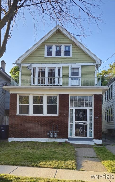 view of front of home with a front yard and a balcony