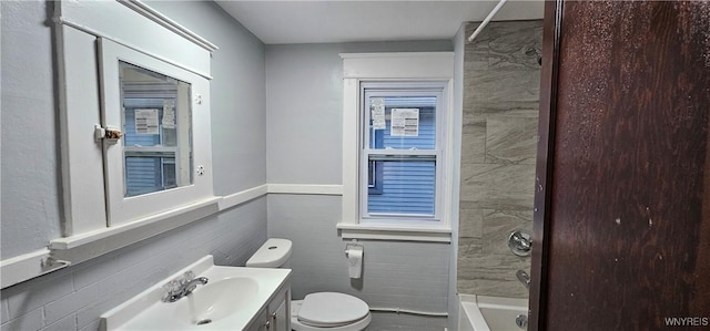 full bathroom with tile walls, shower / bathtub combination, vanity, and toilet