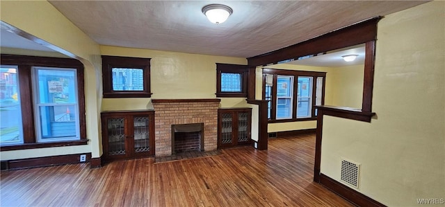 unfurnished living room featuring a fireplace and dark wood-type flooring