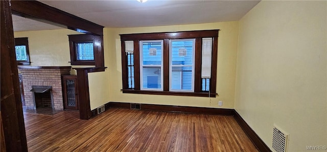 unfurnished living room featuring a brick fireplace and wood-type flooring