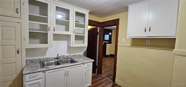 kitchen featuring white cabinets, dark wood-type flooring, light stone countertops, and sink