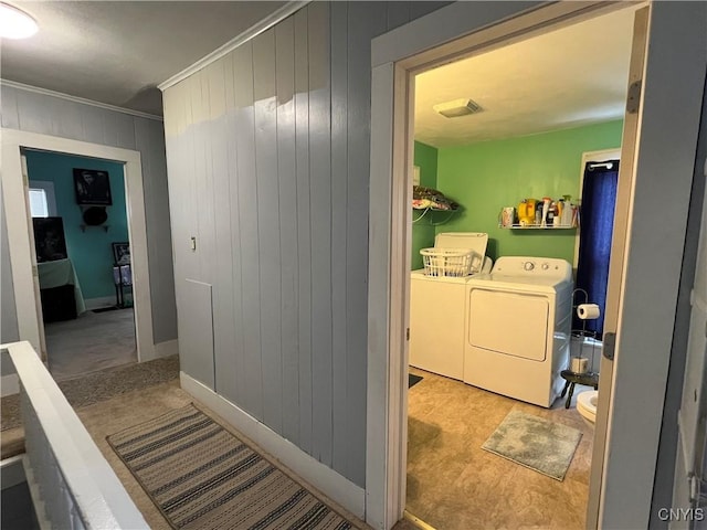 laundry room featuring washer and dryer, ornamental molding, and wood walls