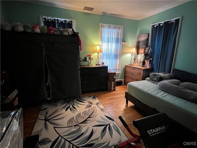 bedroom featuring light hardwood / wood-style floors, a textured ceiling, and crown molding