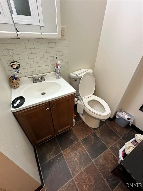 bathroom with toilet, vanity, and backsplash