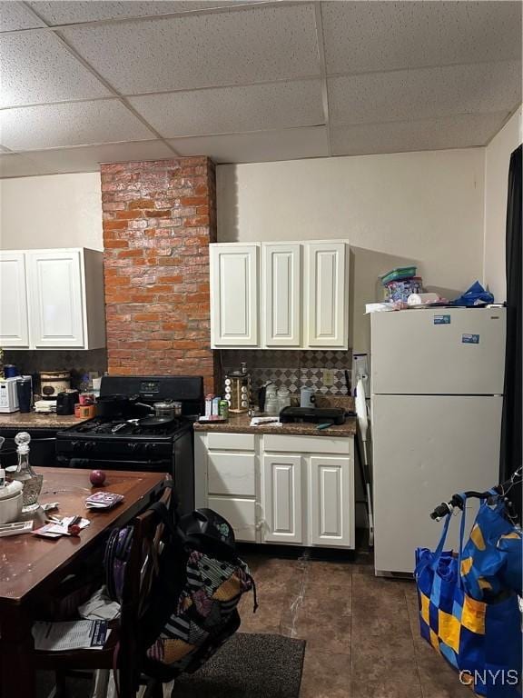 kitchen with a paneled ceiling, white refrigerator, and white cabinets