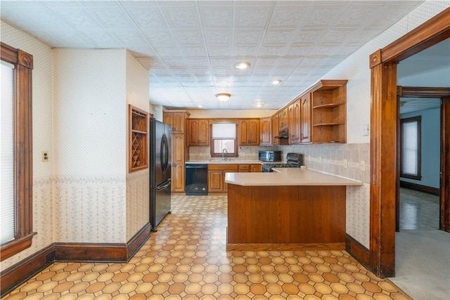 kitchen featuring sink, backsplash, kitchen peninsula, and black appliances