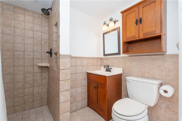 bathroom featuring toilet, vanity, tile walls, tile patterned floors, and a tile shower