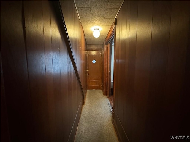 hall with light carpet and wood walls