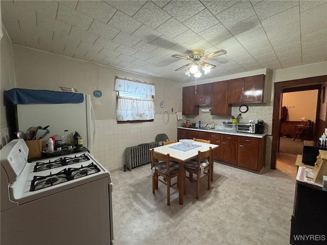 kitchen with ceiling fan, radiator, sink, and white appliances