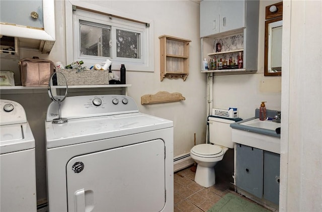 clothes washing area featuring a baseboard radiator, dark tile patterned flooring, and washing machine and dryer