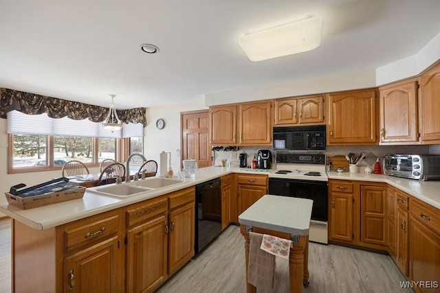 kitchen featuring black appliances, tasteful backsplash, sink, hanging light fixtures, and a center island with sink