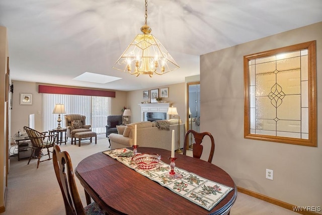 dining space with light colored carpet, a skylight, and an inviting chandelier