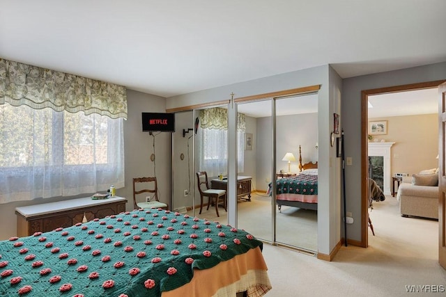 bedroom with two closets, light carpet, and a premium fireplace