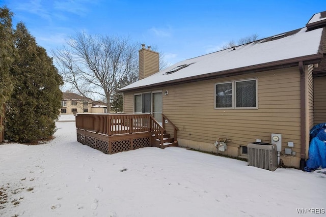 snow covered rear of property featuring a wooden deck and central air condition unit