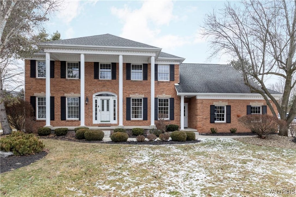 neoclassical home featuring a front lawn