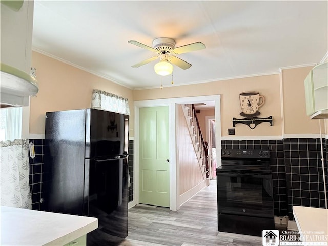 kitchen with light wood-type flooring, black appliances, crown molding, and ceiling fan