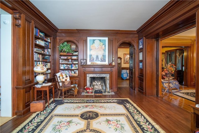 sitting room with dark wood-type flooring, built in shelves, wooden walls, and a fireplace