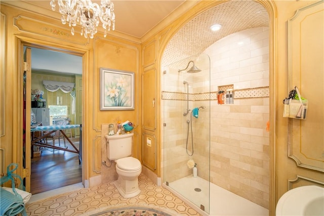 bathroom with toilet, a tile shower, and a notable chandelier