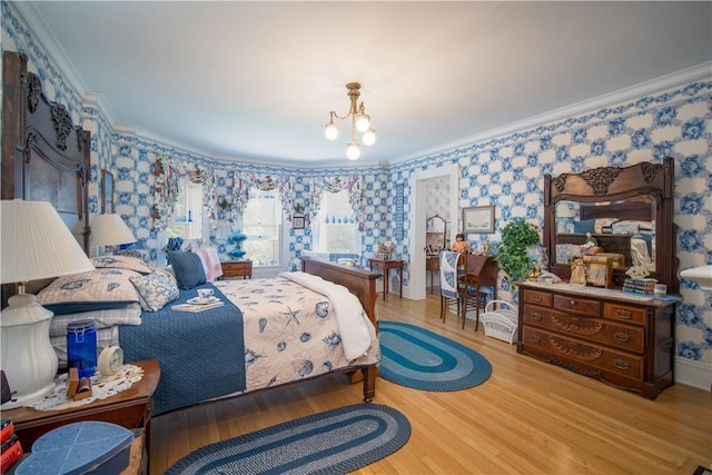 bedroom with light hardwood / wood-style floors, ornamental molding, and an inviting chandelier