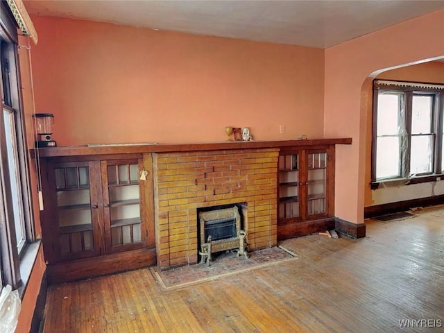 unfurnished living room with hardwood / wood-style flooring and a brick fireplace