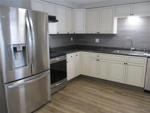 kitchen with appliances with stainless steel finishes, backsplash, wood-type flooring, white cabinets, and sink