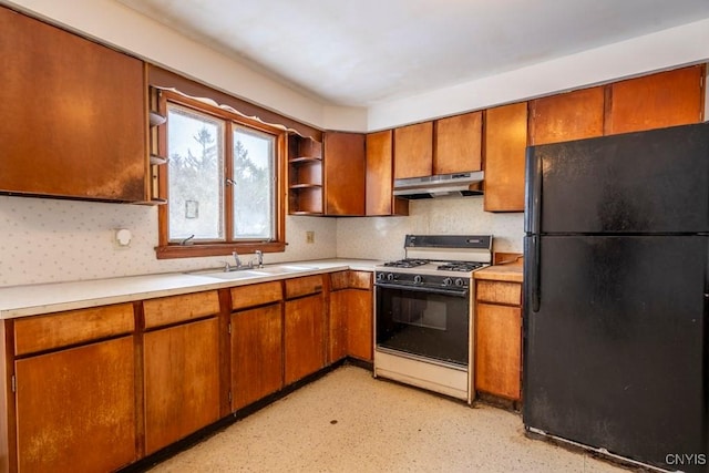 kitchen with black refrigerator, decorative backsplash, sink, and white gas stove