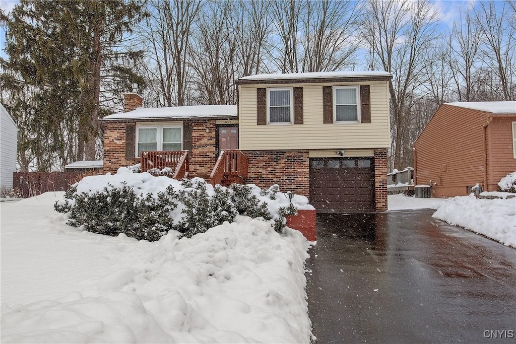 tri-level home featuring central AC and a garage