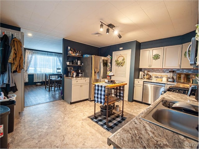 kitchen with light stone countertops, sink, backsplash, and appliances with stainless steel finishes